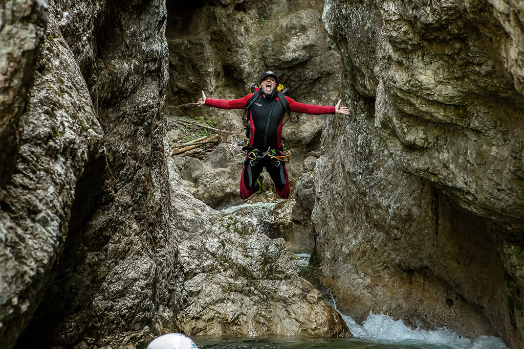 Markus beim Canyoning, springt von einem Felsen in einen Bach.